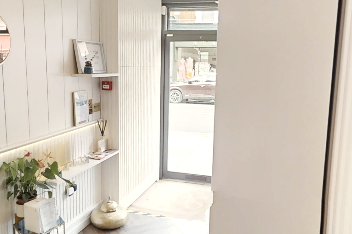A shelf with a reed diffuser and cards beside the street door at Shirland Dental Practice