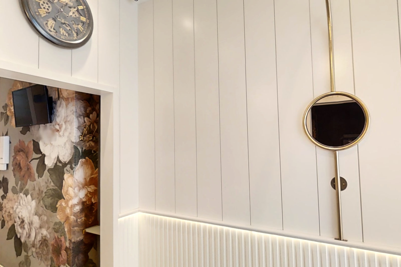 The waiting alcove at Shirland Dental Practice, with floral wallpaper and a round brass mirror