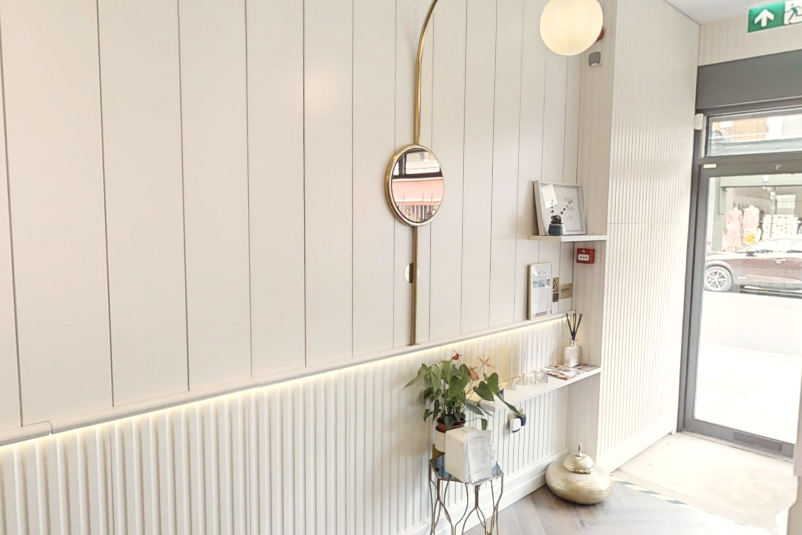Reception at Shirland Dental Practice, with panelled walls, a brass arc lamp over a round mirror and the street door beyond