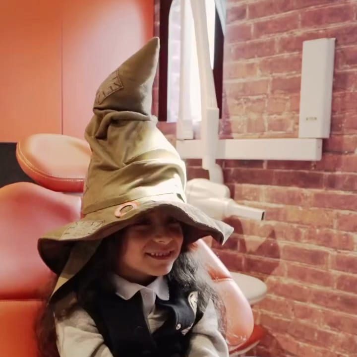 A young patient wearing a sorting hat in the dental chair at Queen’s Park