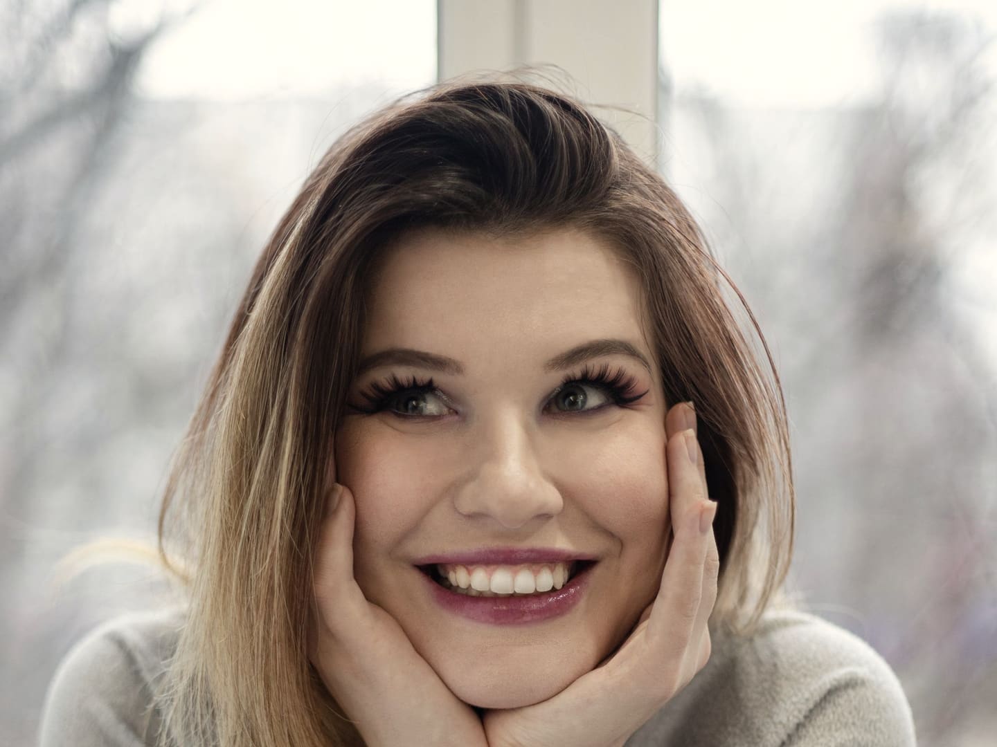 Woman smiling in soft window light after teeth whitening